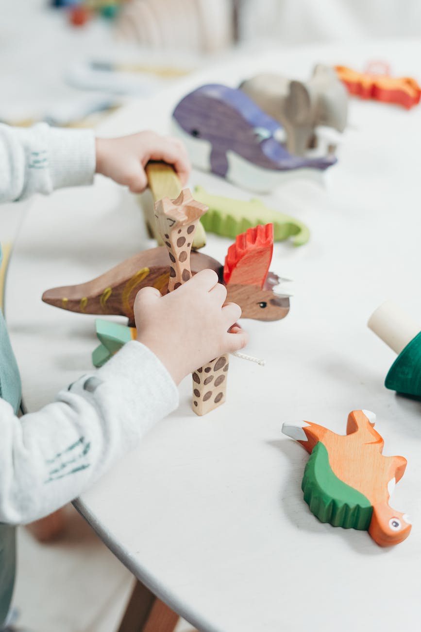 child holding brown and green wooden animal toys